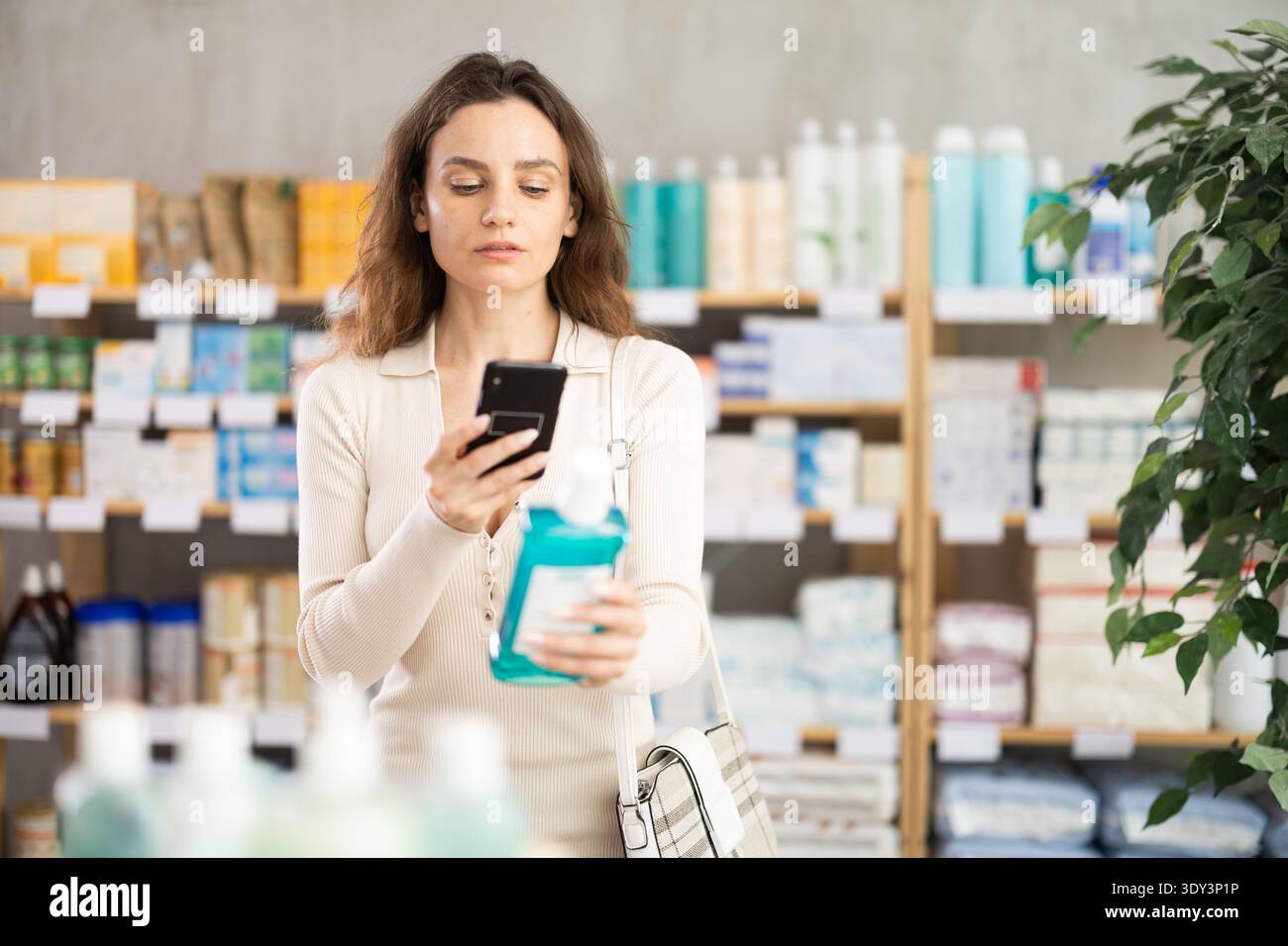 Donna in abiti estivi scansiona il codice su collutorio medicinale per controllare la data di scadenza Foto Stock