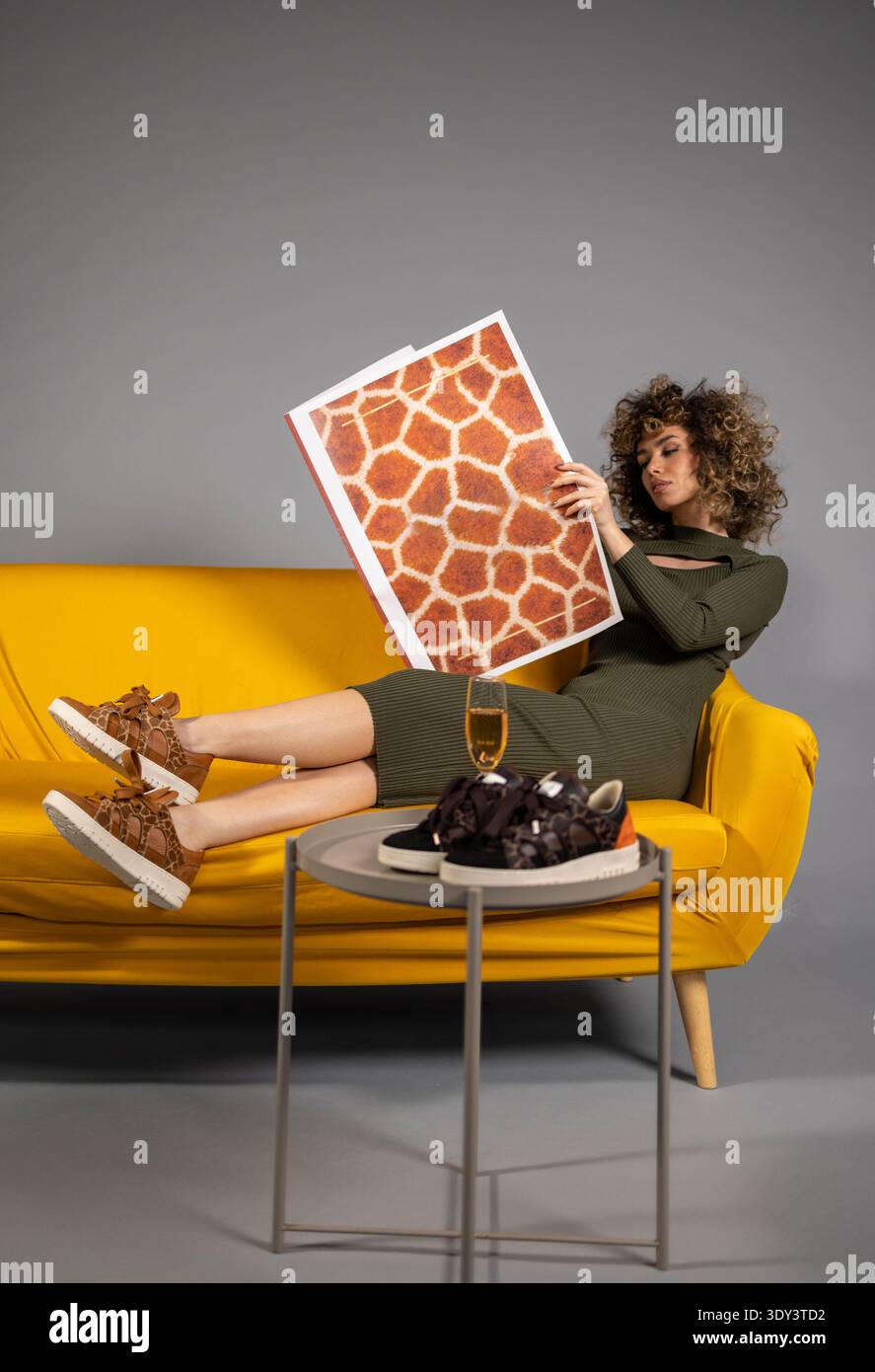Donna sul divano che posa in studio Foto Stock