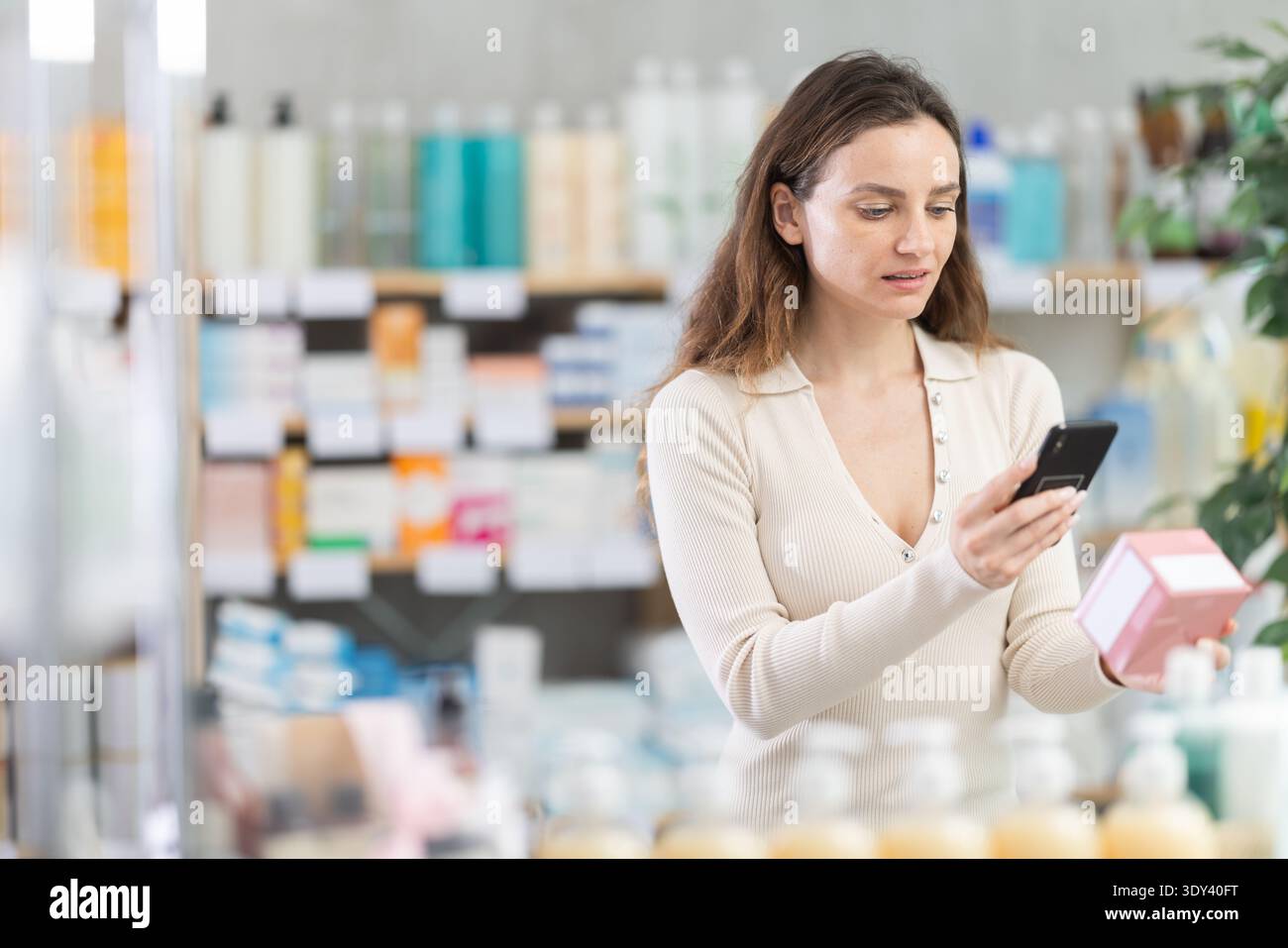 Donna in abiti estivi scansiona il codice sulla confezione dell'unguento per controllare la data di scadenza Foto Stock
