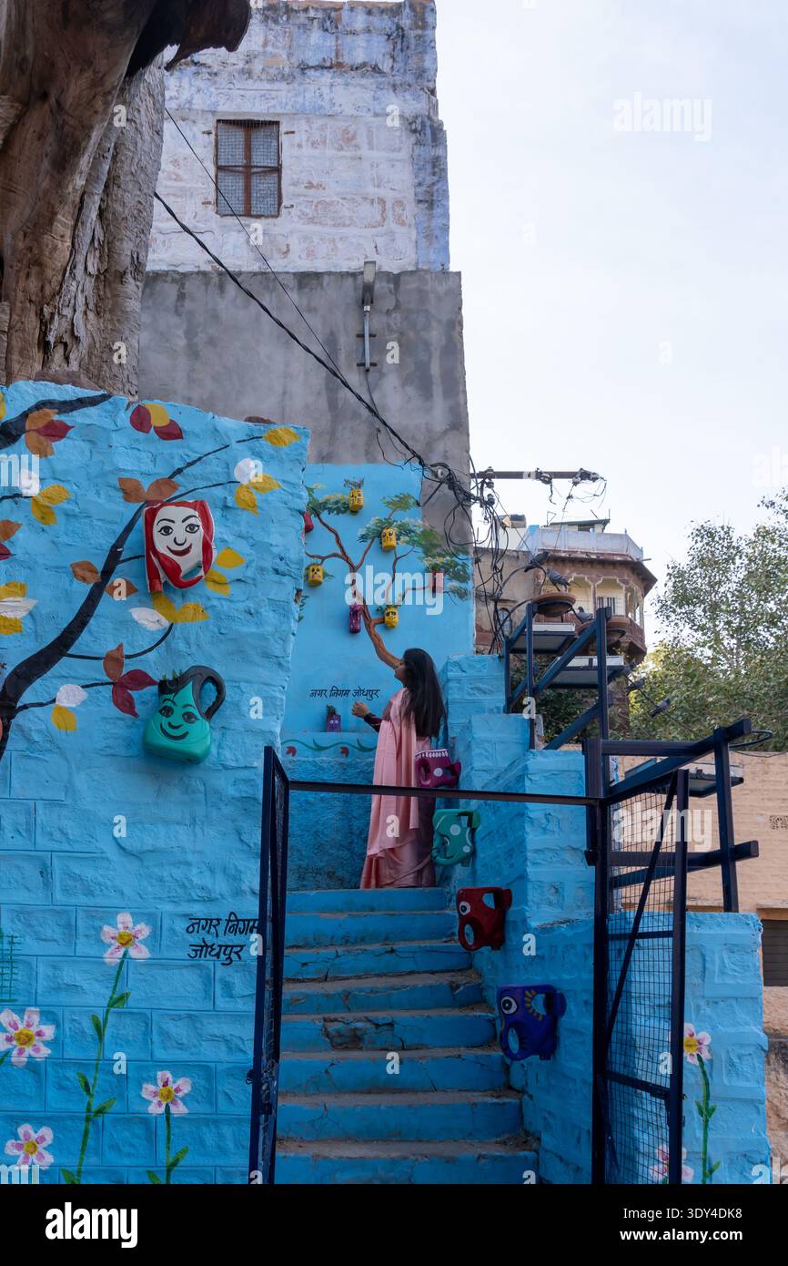 Jodhpur, Rajasthan, India - 30 gennaio 2026: Una giovane donna in piedi sulle scale dipinte di blu nella vecchia città di Jodhpur, Rajasthan, India. Foto Stock