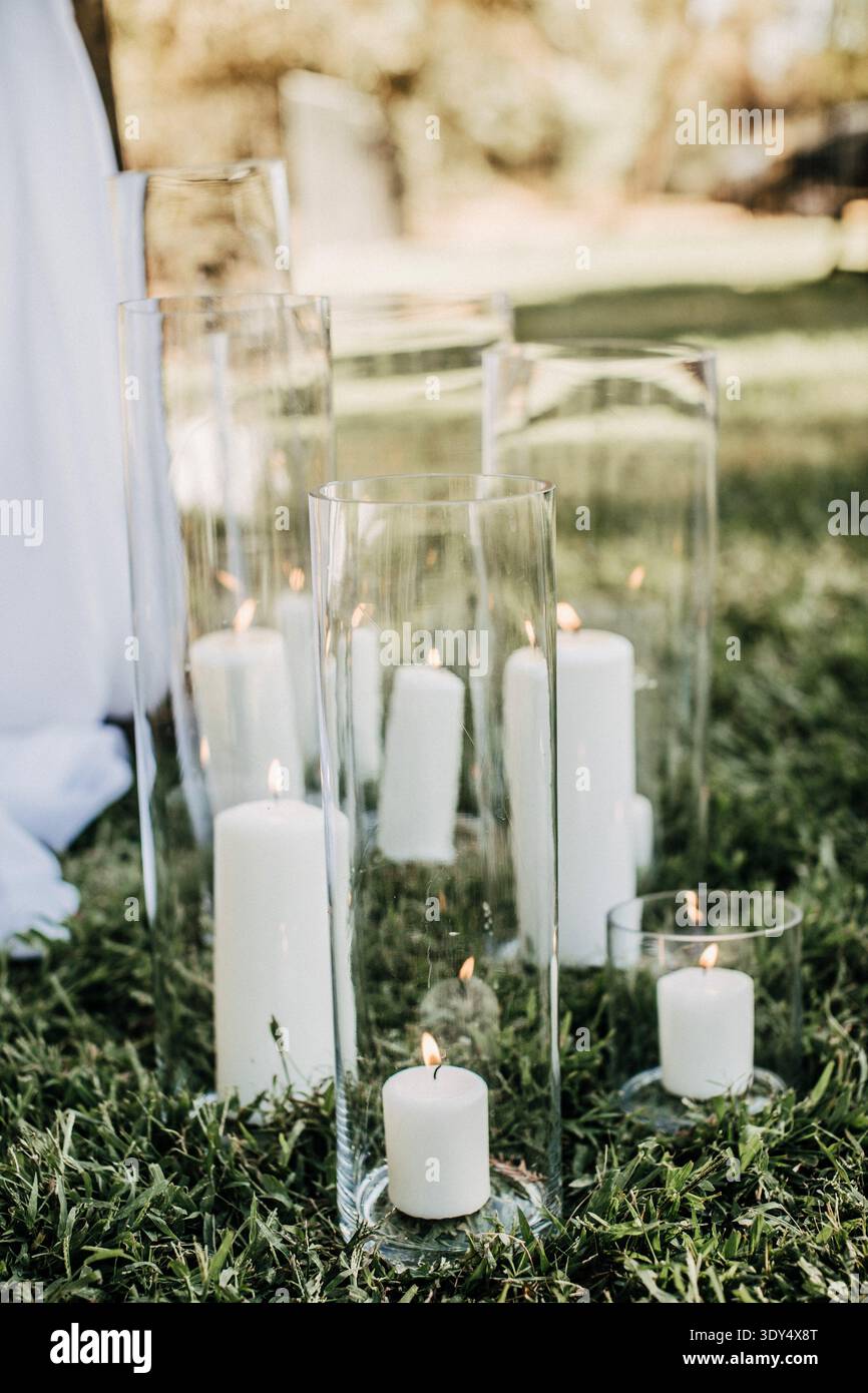 candele bianche in cilindri di vetro che decorano la sala per cerimonie nuziali all'aperto Foto Stock