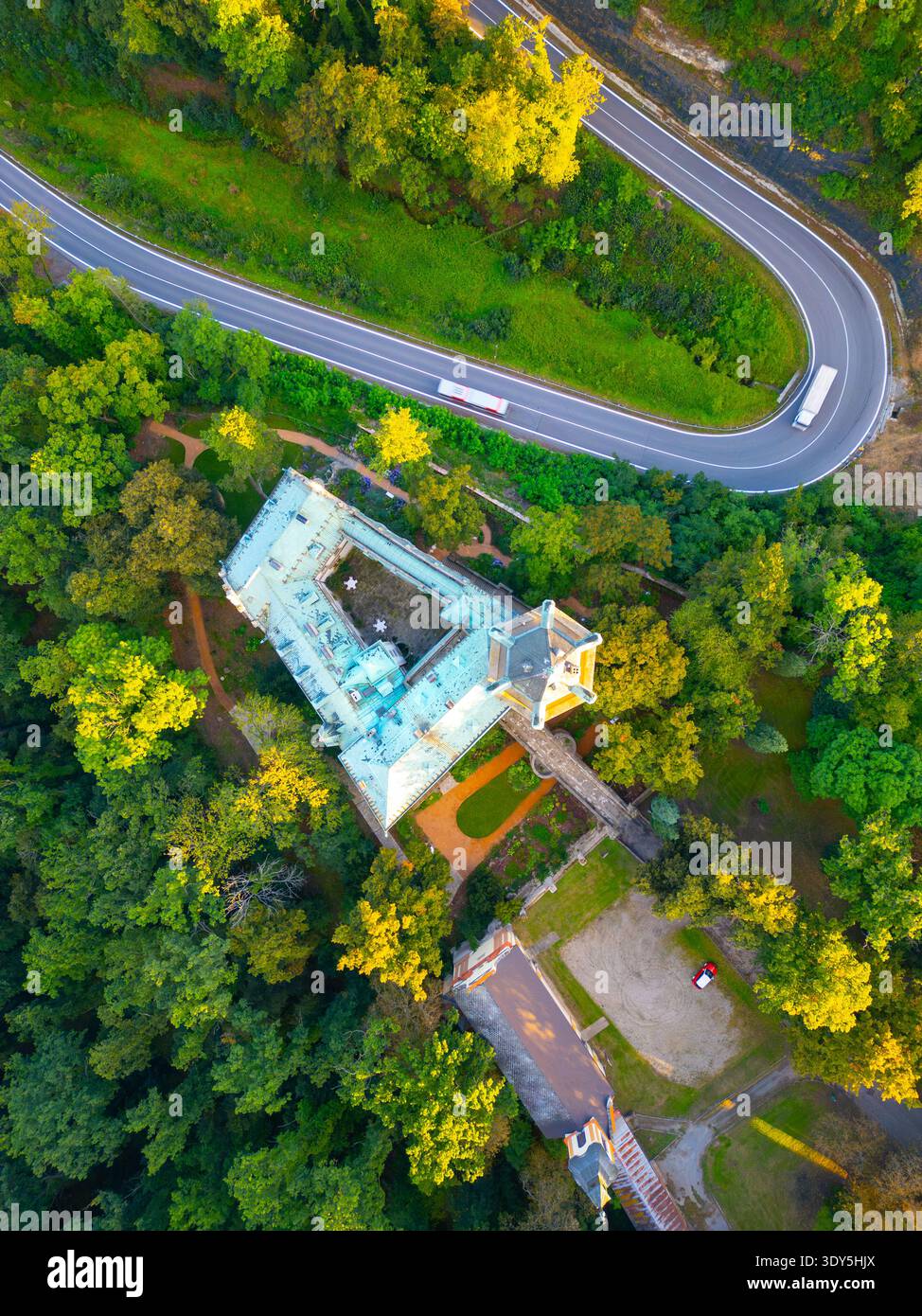 Questa vista aerea mostra il castello di Stranov circondato da una vegetazione lussureggiante nella Boemia centrale. Una strada tortuosa conduce oltre il castello, evidenziando la sua posizione panoramica. Foto Stock