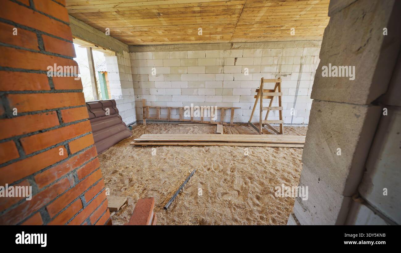 Scala e cavalletto in legno in piedi in casa in costruzione Foto Stock
