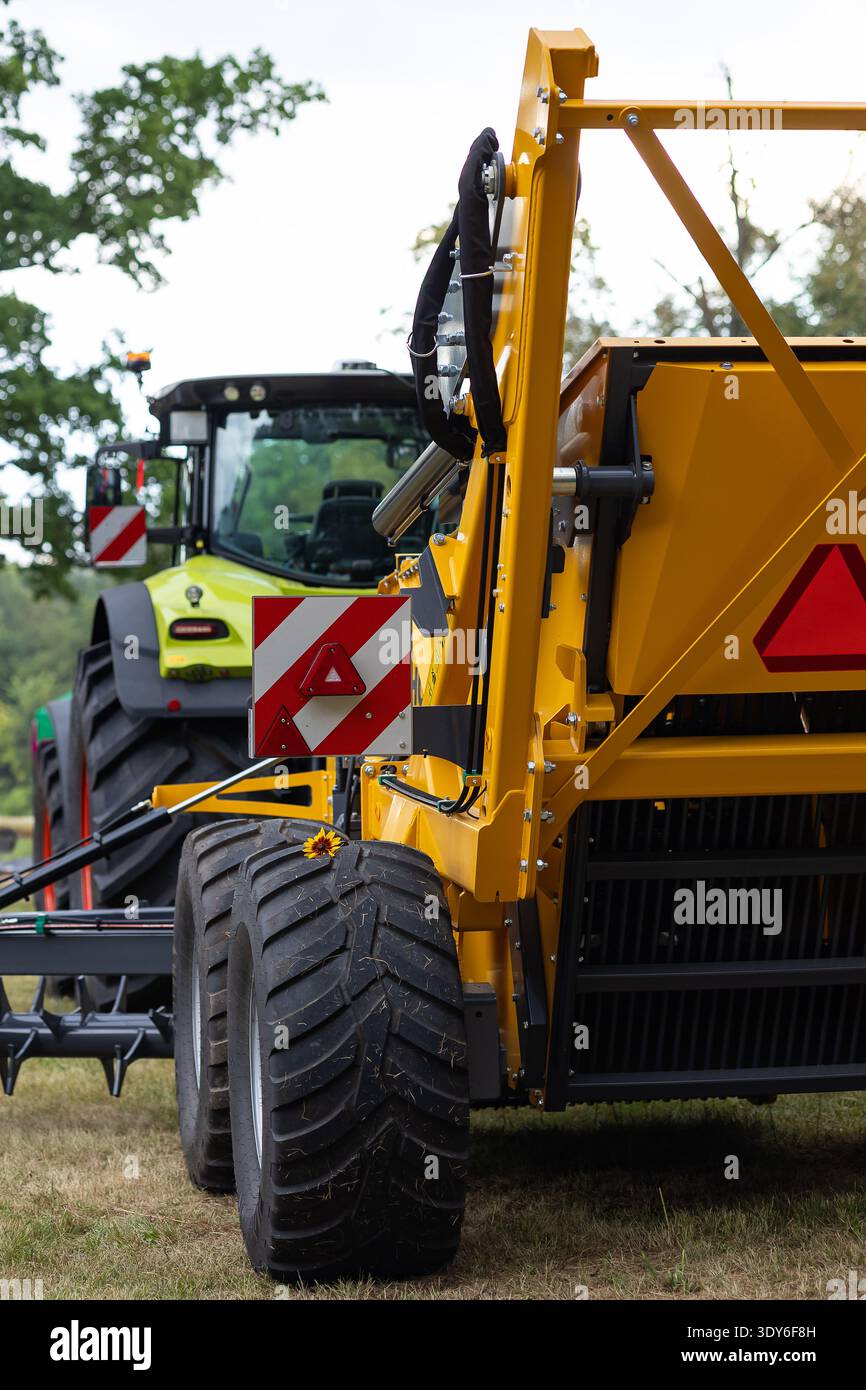 Moderne macchine agricole con segnaletica di sicurezza rossa e bianca e riflettori per lavori in campo a molla sicuri. Attrezzature agricole professionali Foto Stock