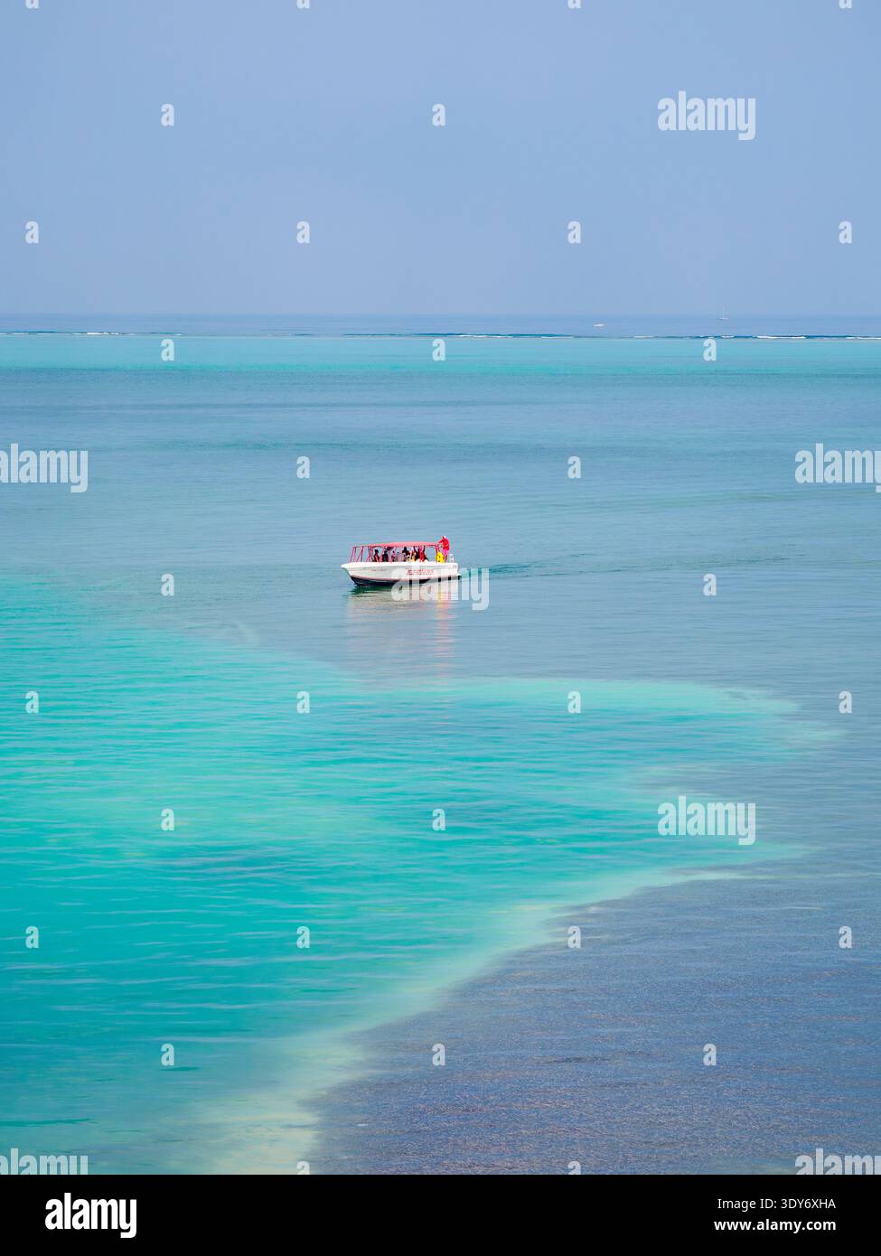 La barca turistica attraversa le acque cristalline vicino a Caye Caulker nel quartiere Belize durante una giornata di sole Foto Stock