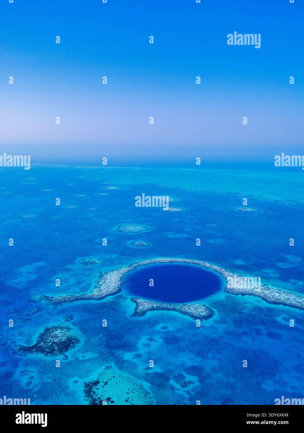 Esplora il cerchio blu profondo nell'oceano a Lighthouse Reef vicino al Belize, con cieli limpidi e acque vivaci Foto Stock