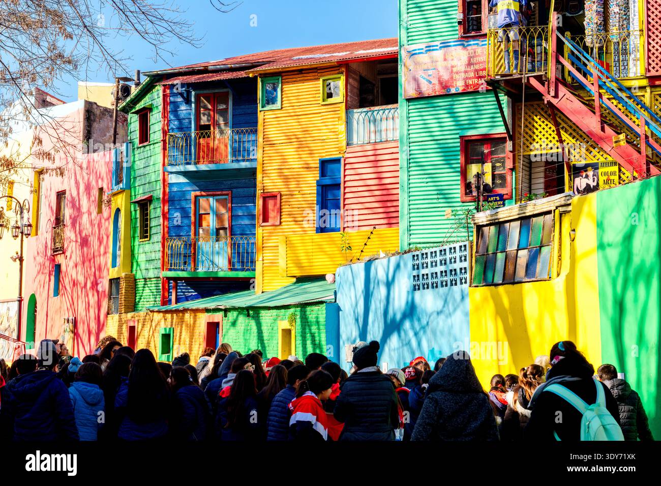 I turisti esplorano case vivaci e pareti luminose a Caminito mentre si godono la loro visita a la Boca a Buenos Aires, Argentina Foto Stock