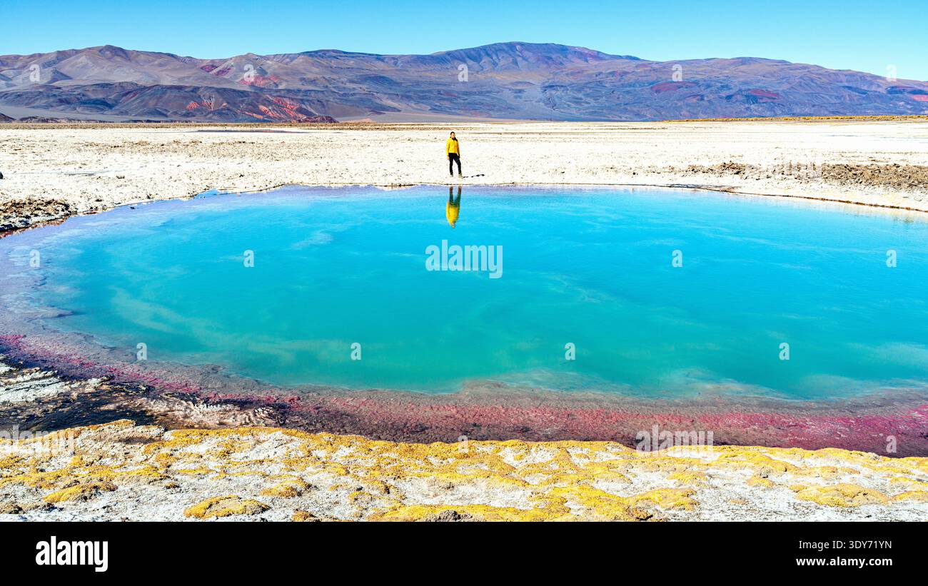 Il turista osserva il laghetto di acqua salata blu brillante in un paesaggio desertico vicino ad Antofalla in Argentina Foto Stock