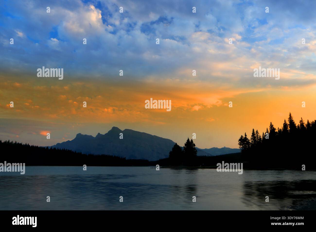Vista del tramonto sul lago Jack con Montagne Rocciose e alberi vicino a Banff, Alberta, Canada Foto Stock
