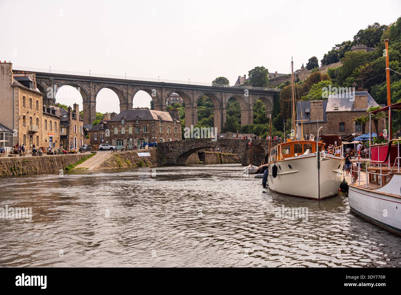 Le barche navigano lungo il fiume Rance sotto il viadotto Dinan e l'antico ponte in pietra in Bretagna in una giornata di sole Foto Stock