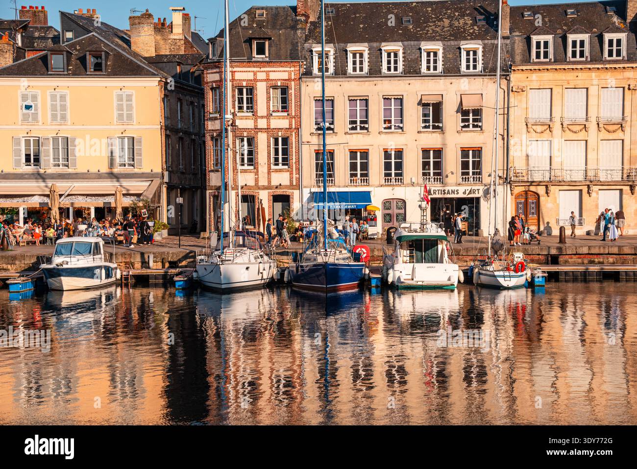 Case sul lungomare e barche al porto Vieux Bassin di Honfleur durante il giorno con gente che si gode i dintorni Foto Stock