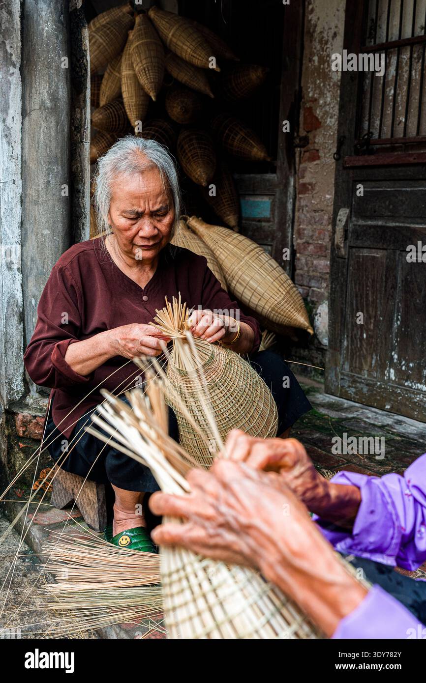 Realizzare trappole per pesci di bambù ad Hanoi con mani esperte e sforzi condivisi dalle donne Foto Stock