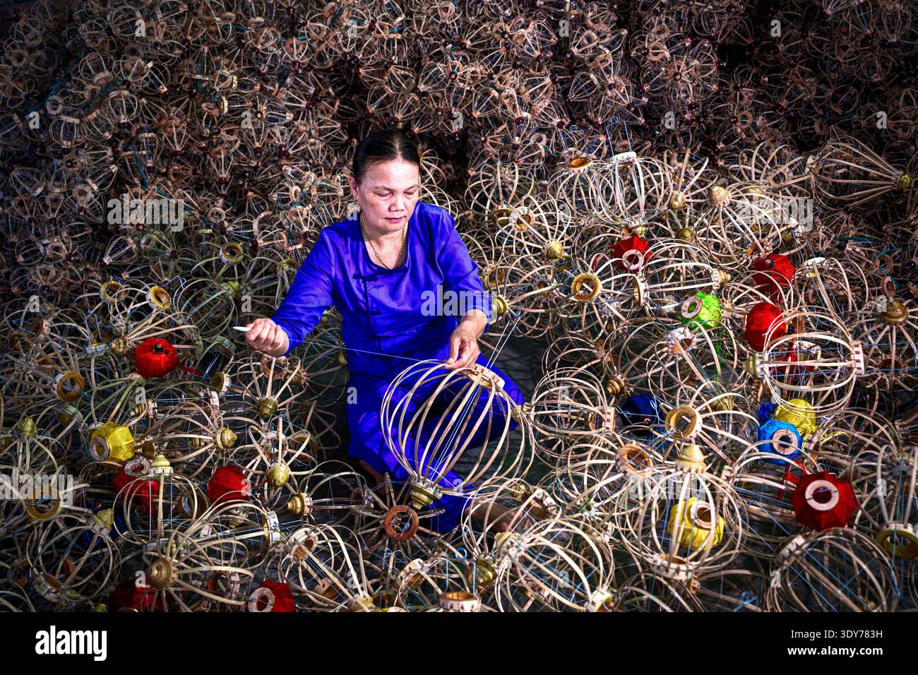 La donna assembla lanterne tradizionali a Hoi An come parte del patrimonio artigianale locale in Vietnam durante le ore diurne Foto Stock