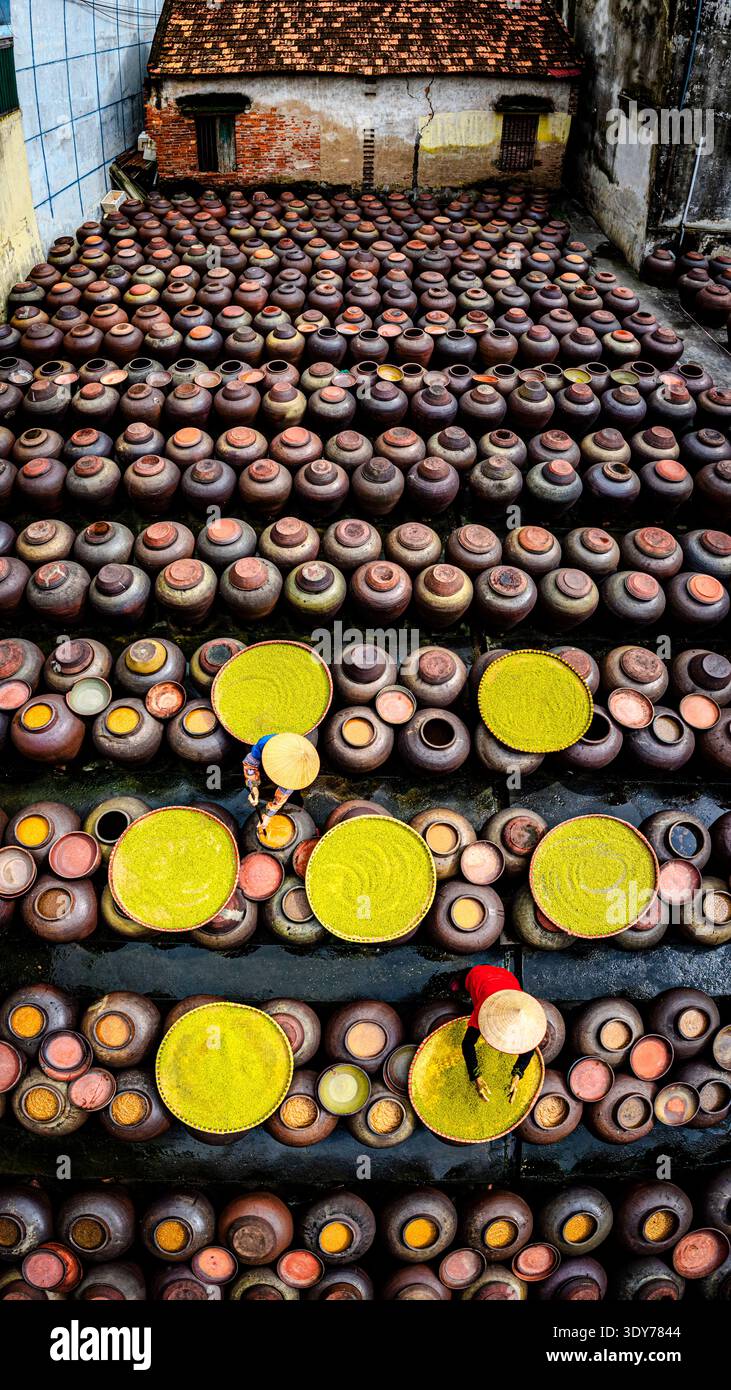 I lavoratori preparano la salsa di soia in grandi pentole dall'alto ad Hanoi, Vietnam, concentrandosi sui metodi tradizionali e sulle pratiche locali Foto Stock