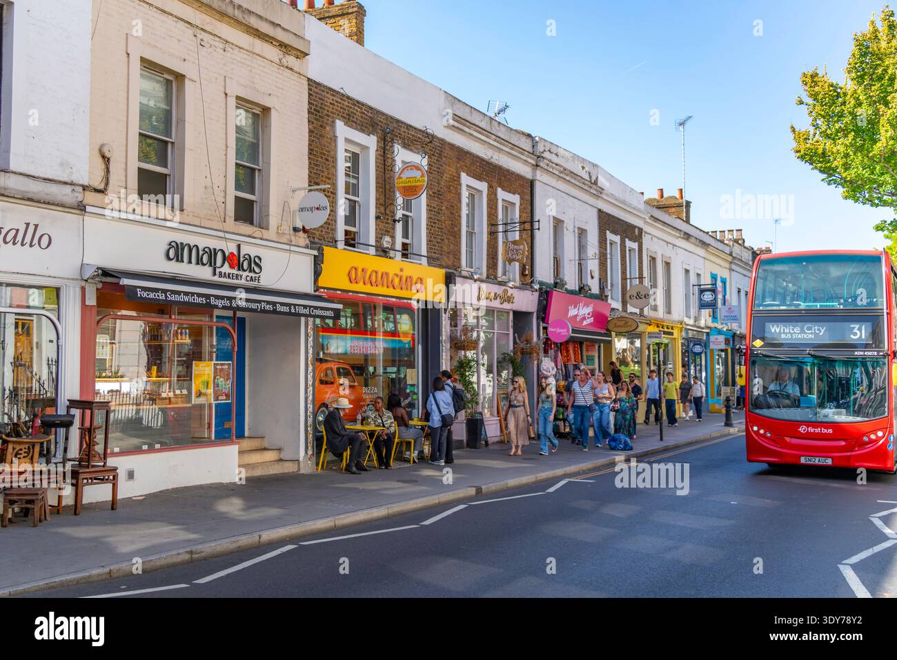 Le persone amano l'estate a Kensington con negozi locali e un autobus che passa in una giornata di sole a Londra, Inghilterra, Regno Unito Foto Stock