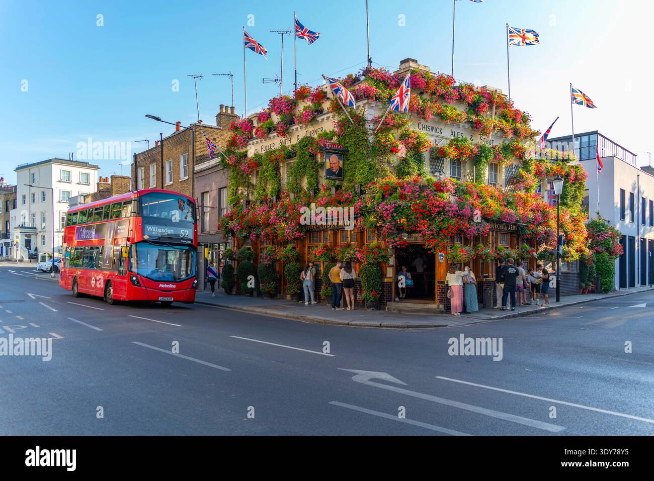 Brillante giornata estiva al Churchill Arms con fiori e visitatori a Kensington Londra Foto Stock