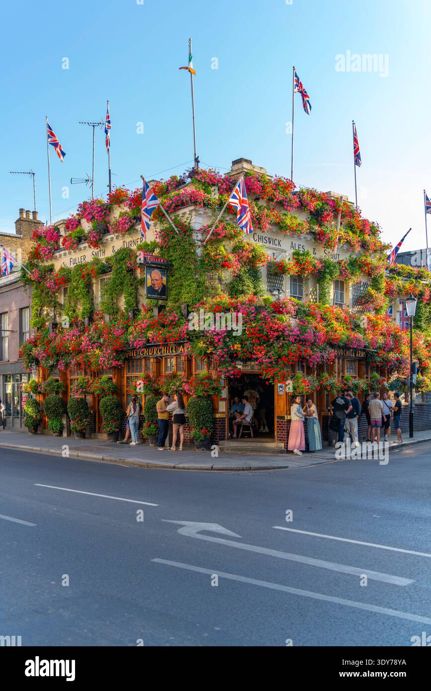 Pub con fiori e bandiere attira i visitatori durante l'estate a Kensington, Londra, con un'atmosfera vivace e una scena vivace Foto Stock