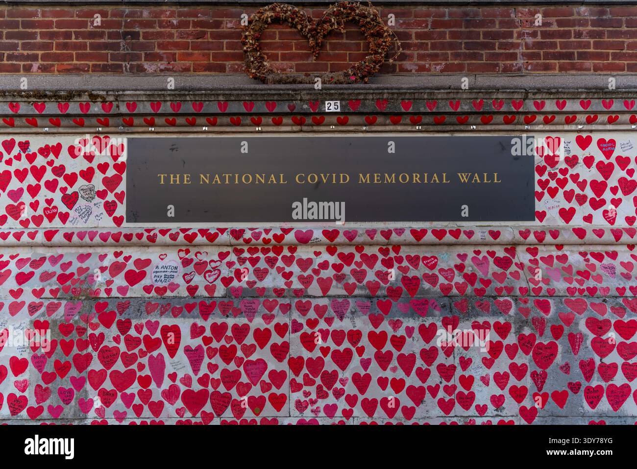 Le decorazioni del cuore coprono il National Covid Memorial Wall come tributo a coloro che si sono persi durante la pandemia a Londra, Regno Unito Foto Stock