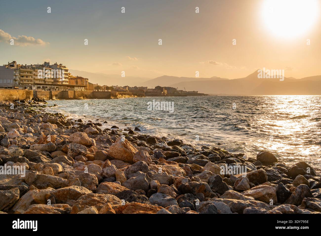 Tramonto sulla costa con rocce ed edifici a Heraklion, Creta, Grecia Foto Stock