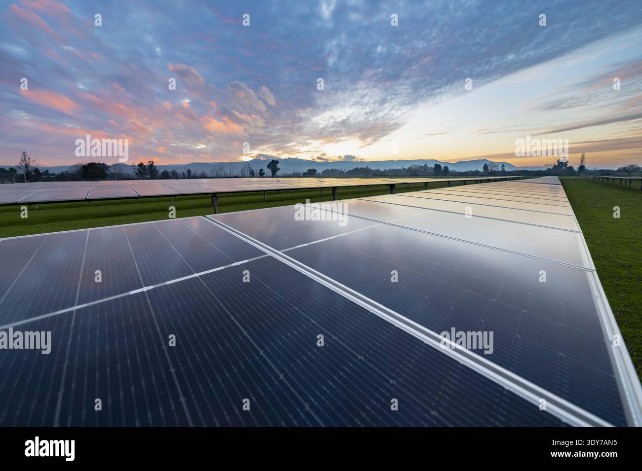 Immagine HDR panoramica di pannelli fotovoltaici solari in un paesaggio rurale durante il crepuscolo, che mostra la tecnologia dell'energia pulita e lo sviluppo sostenibile. Foto Stock