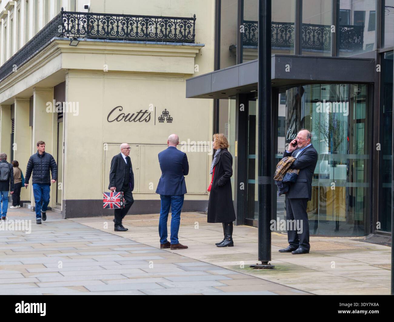 Professionisti e lavoratori cittadini ben vestiti e adatti si riuniscono fuori dalla prestigiosa sede di Coutts & Co. Al 440 The Strand, Londra, nel febbraio 2026. Fondata nel 1692, Coutts è una delle banche private più esclusive al mondo, che richiede ai clienti di mantenere almeno 1 milione di sterline in attività investibili Foto Stock