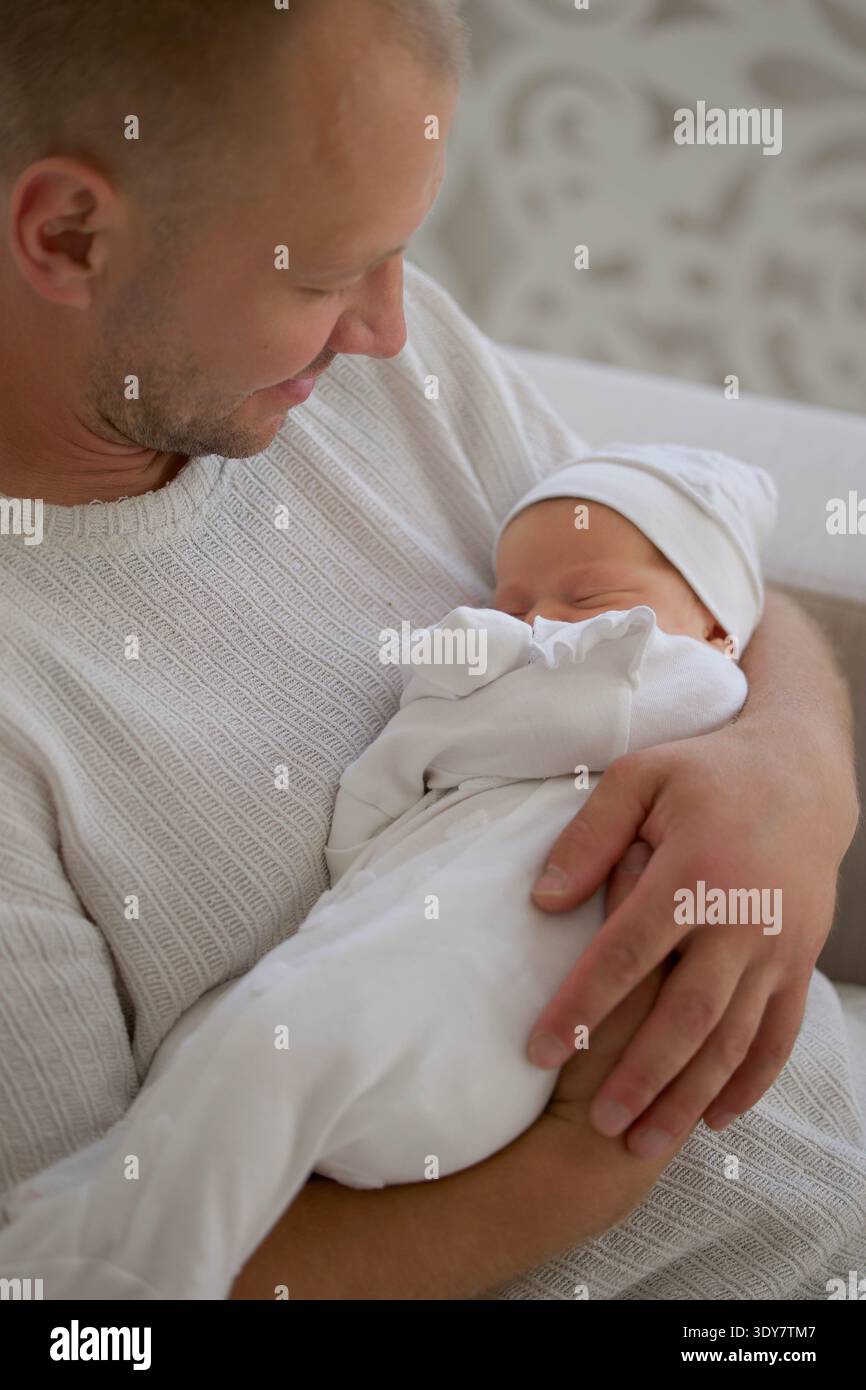 Padre che tiene dormiente neonato a casa Foto Stock