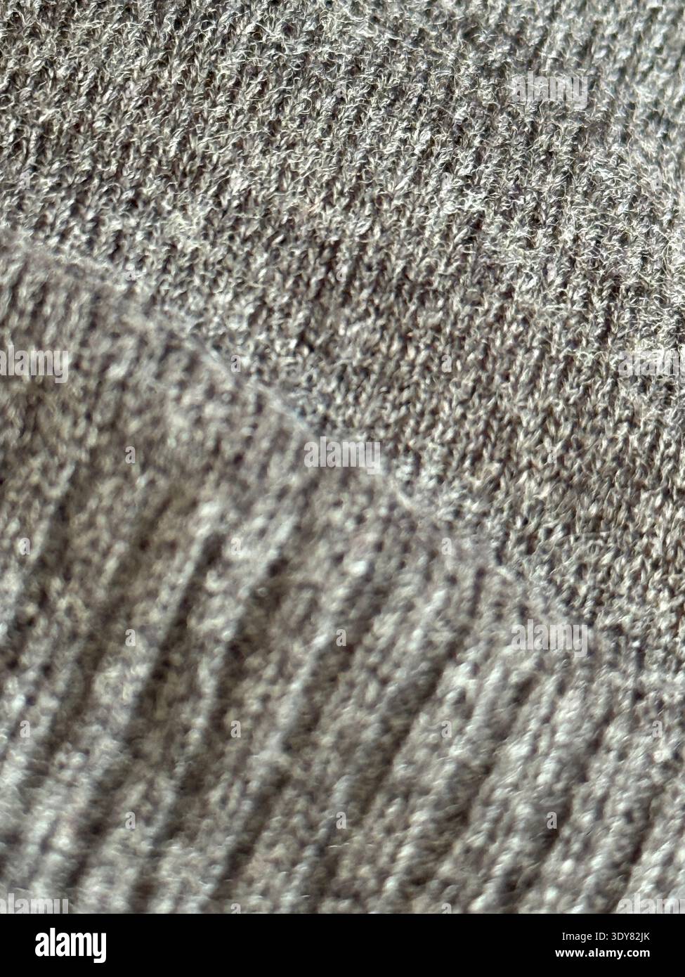 Primo piano in tessuto grigio lavorato a maglia con motivi dettagliati, ideale per lo sfondo tessile. Foto mobile Foto Stock