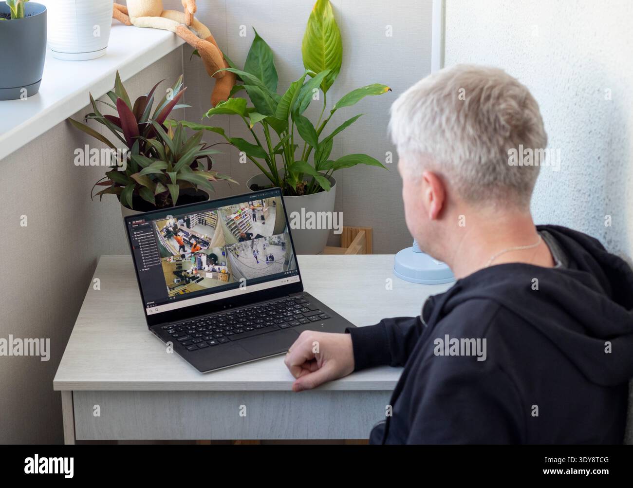 L'uomo controlla le riprese delle telecamere a circuito chiuso sul suo computer portatile Foto Stock