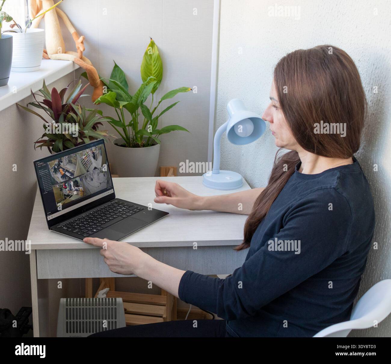 Una donna guarda le riprese delle telecamere a circuito chiuso sul suo computer portatile Foto Stock