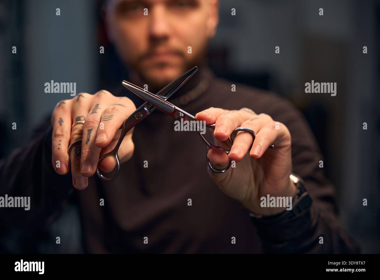 Primo piano di mani maschili con tatuaggio che tiene le forbici in mano Foto Stock
