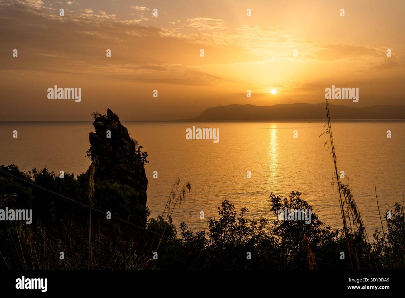 Tramonto dorato incorniciato da scogliere rocciose e mare Mediterraneo Foto Stock