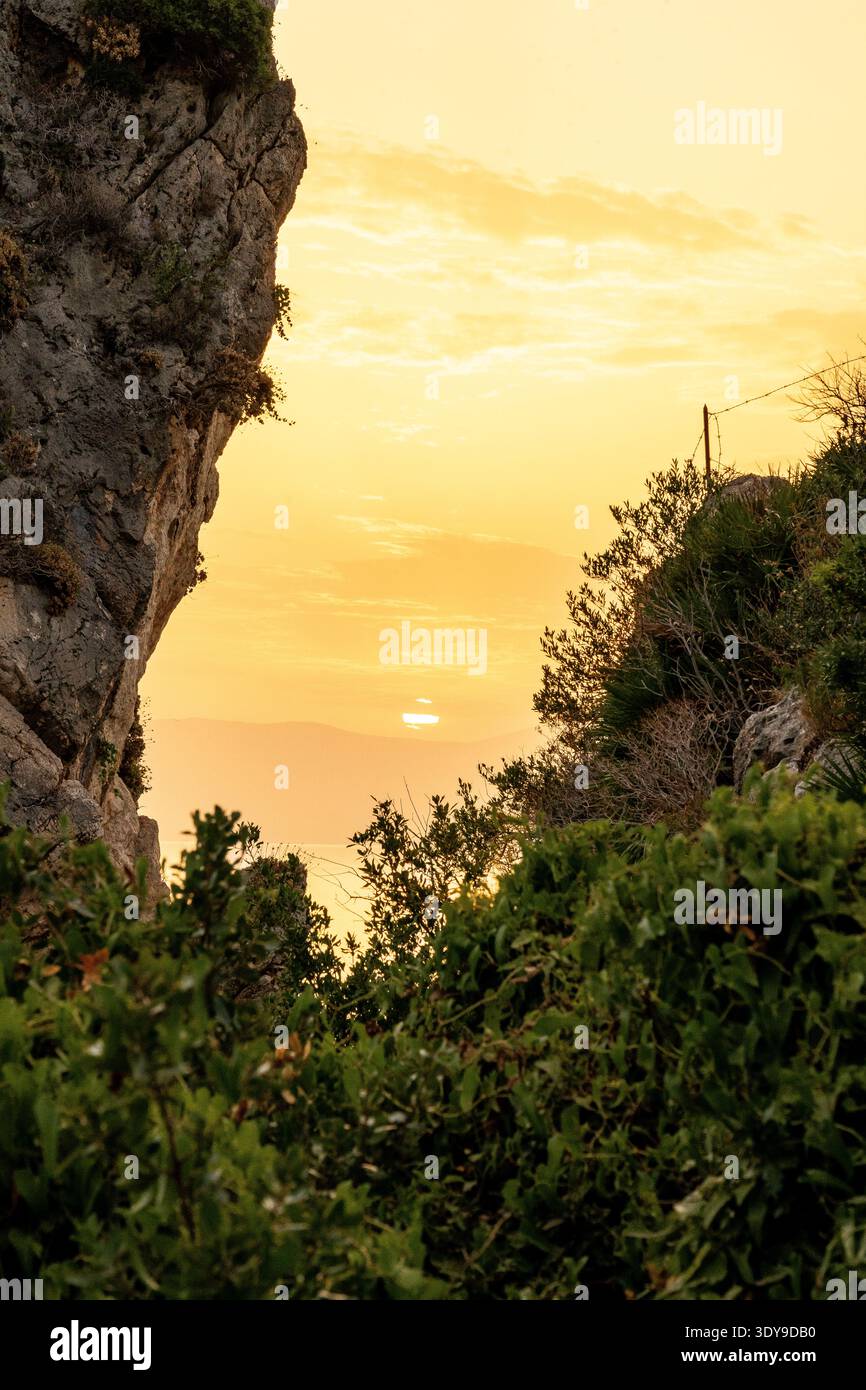 Tramonto dorato incorniciato da scogliere rocciose e mare Mediterraneo Foto Stock