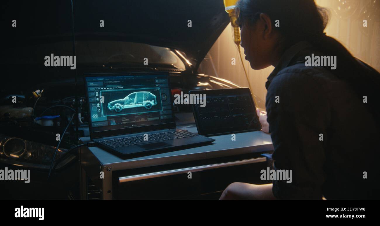 Tecnico donna che analizza il gemello digitale del veicolo su un laptop, con modelli 3D che mostrano lo stato dei componenti interni. Contemporaneamente, la donna interagisce con il tablet per tenere traccia delle curve delle prestazioni e dei registri di sistema. Foto Stock