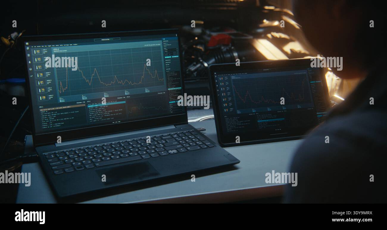 Primo piano della diagnostica automobilistica High Tech con laptop e tablet collegati all'ECU del veicolo. Interfaccia dettagliata del software diagnostico. Concetto di trasformazione digitale del settore delle riparazioni automobilistiche. Foto Stock