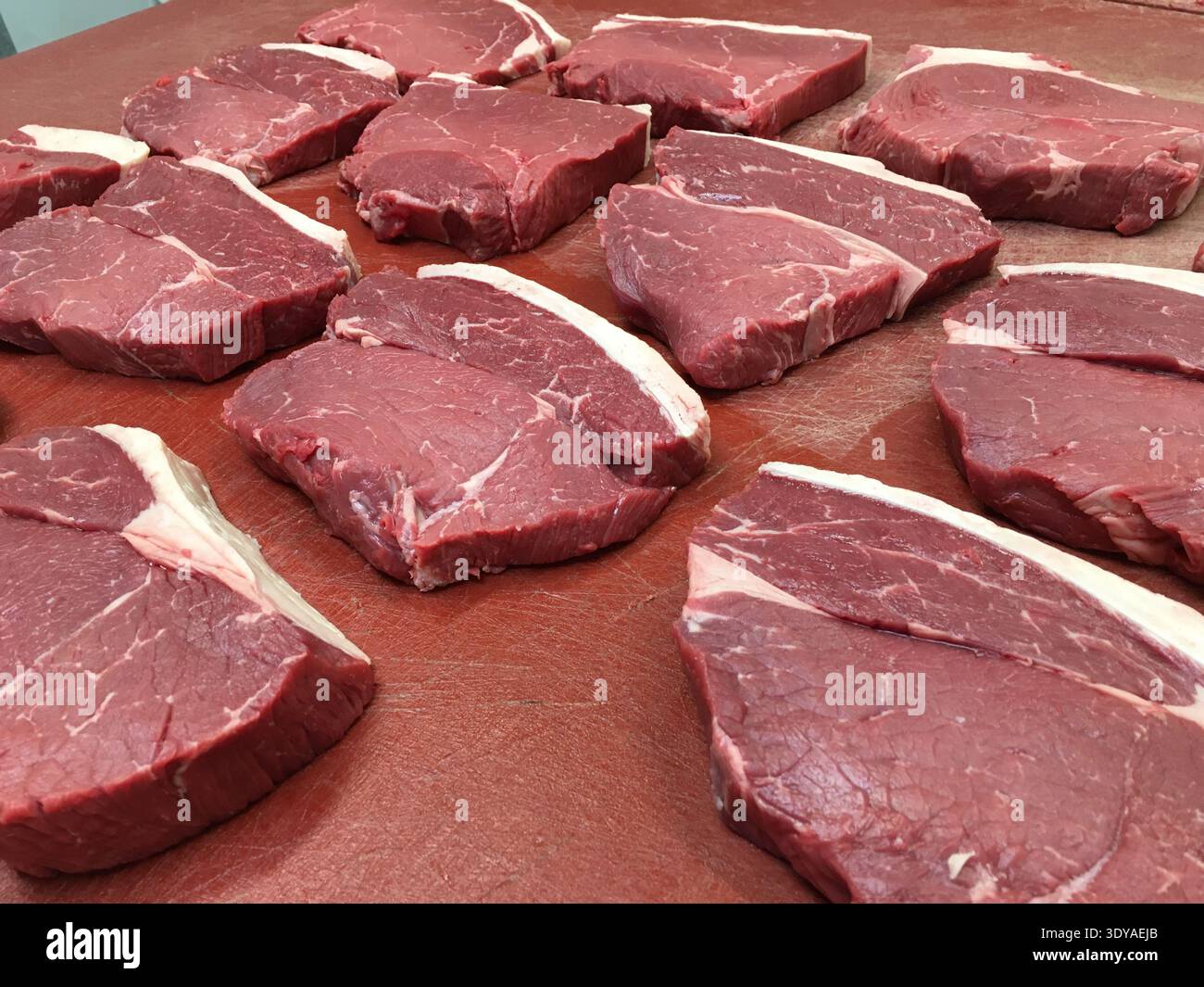 Bistecche di manzo britannico di prima qualità su un tavolo da macellaio rosso Foto Stock
