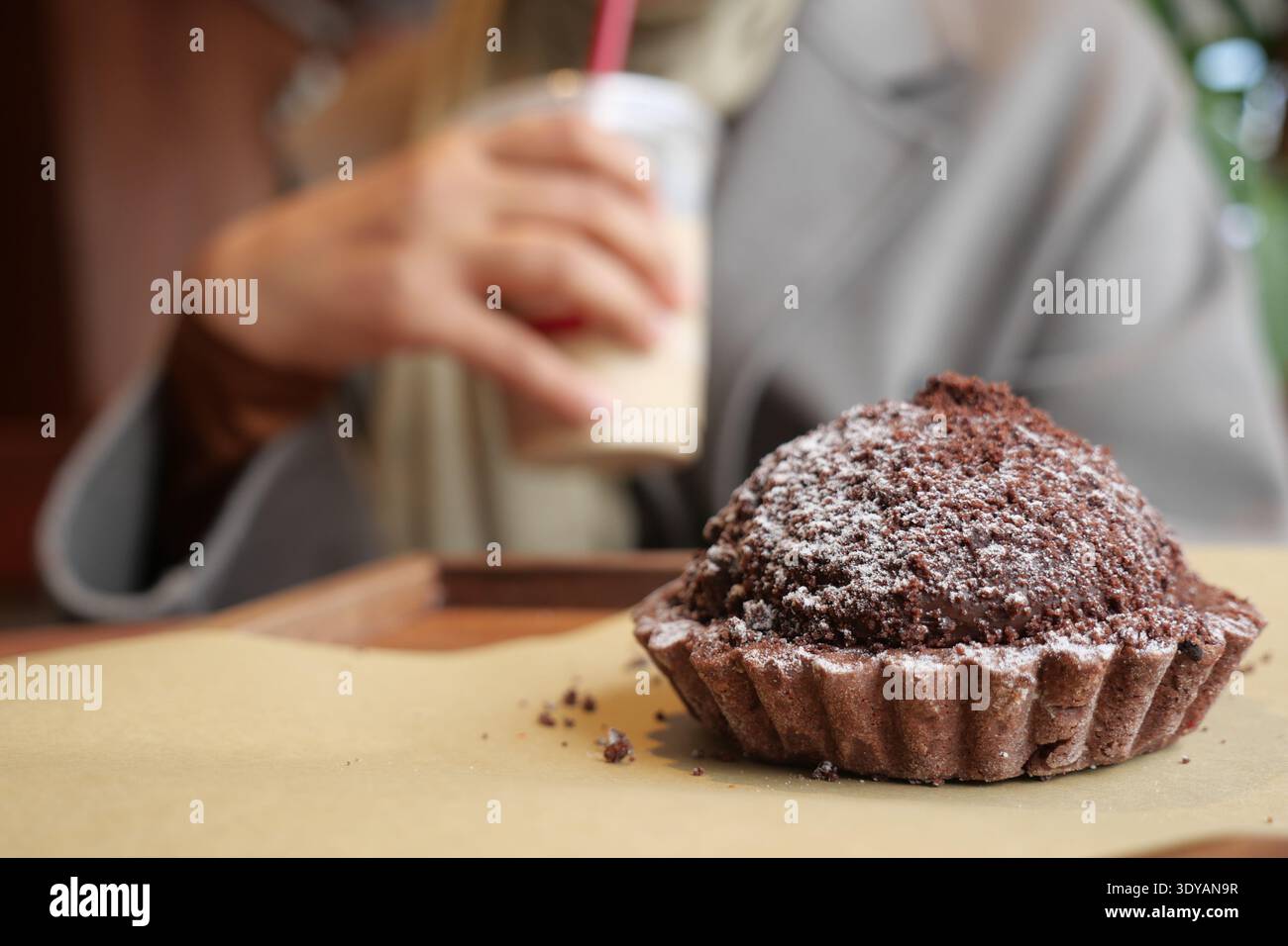 Muffin al cioccolato su un tavolo con una bevanda in mano Foto Stock