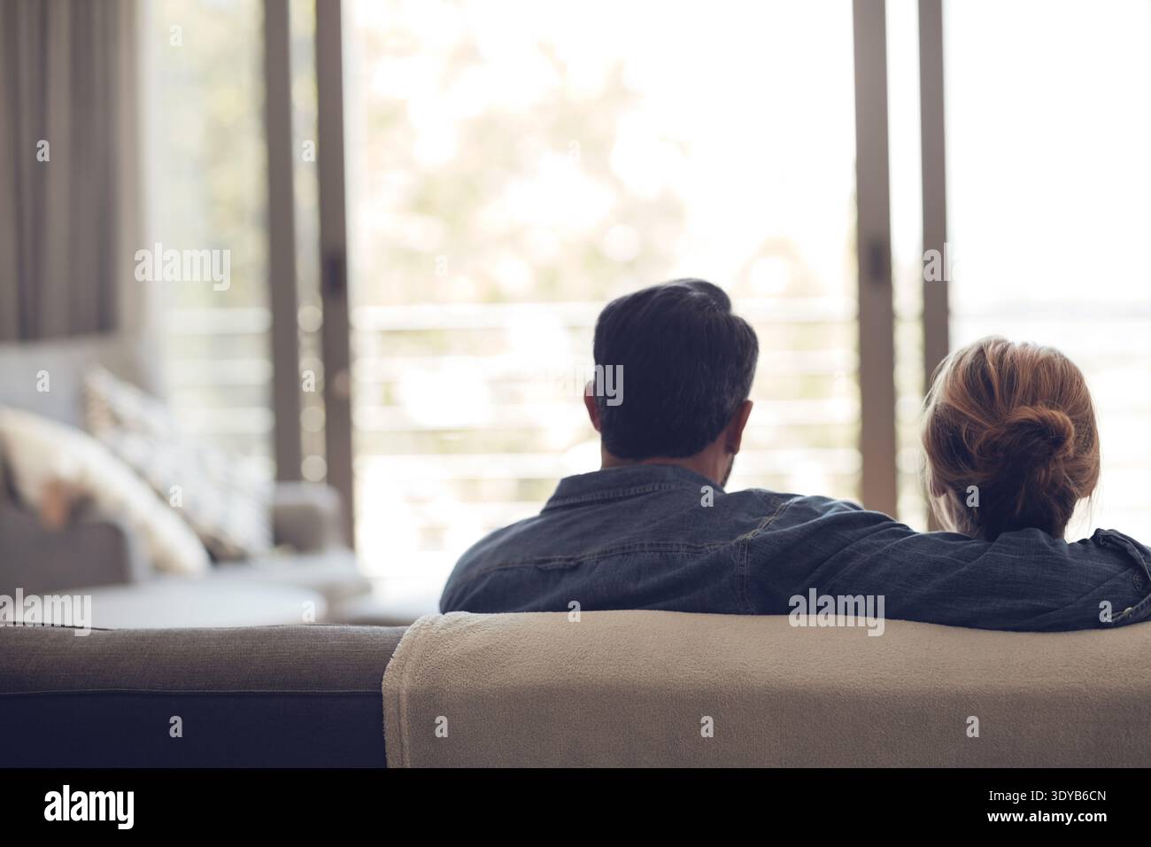 Torna, abbraccia o coppia sul divano con connessione, rilassati e legati insieme durante il weekend. Comfort, bokeh e persone in casa con abbraccio, romantico Foto Stock