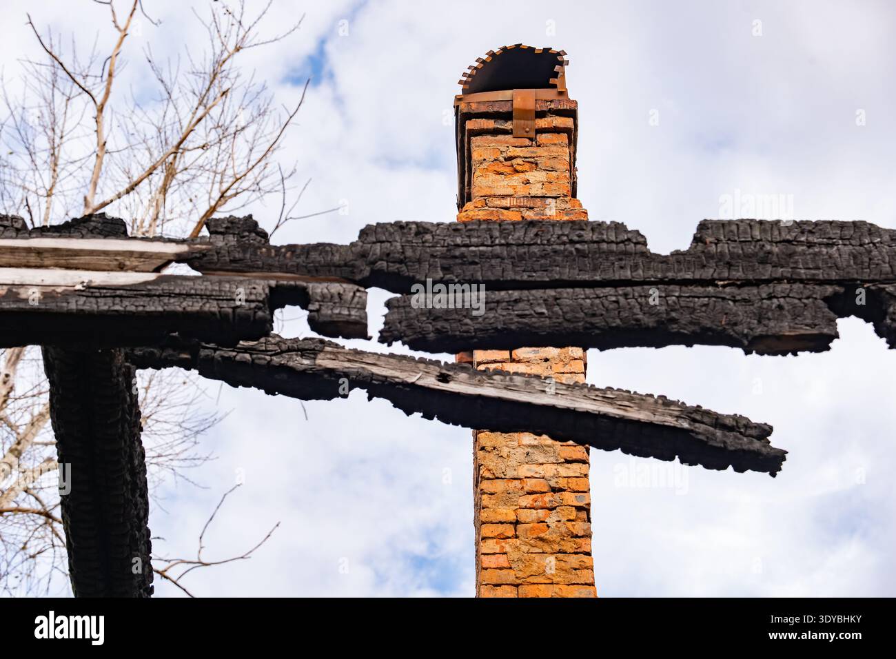 Resti di legno carbonizzato e camino in mattoni in piedi dopo il disastro dell'incendio della casa Foto Stock