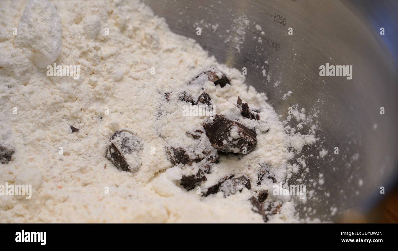 Pezzi di cioccolato e farina nel recipiente per la preparazione dei biscotti Foto Stock
