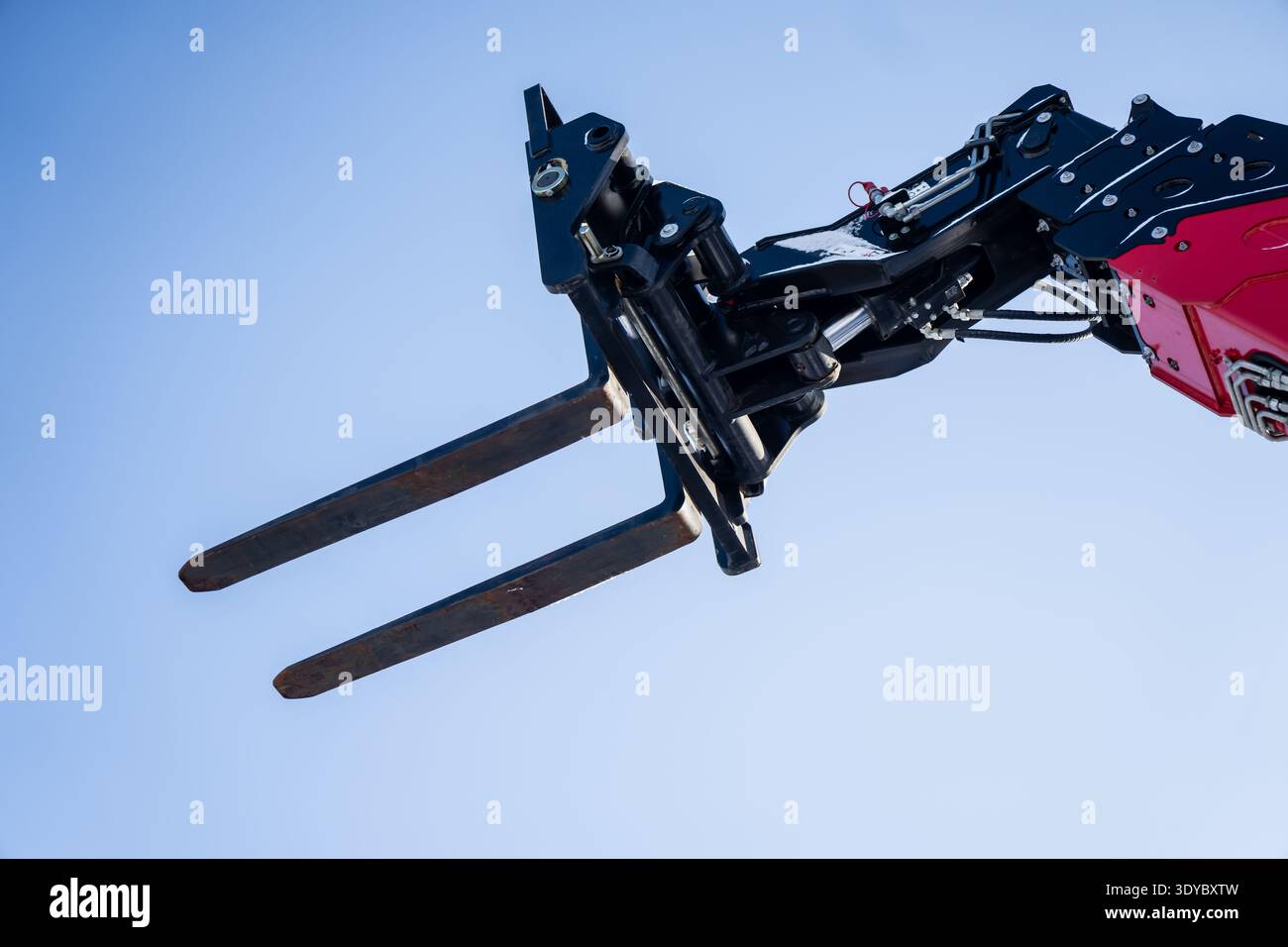 Forche per sollevamento braccio o movimentatore telescopico in aria, forche per pallet in metallo e giunti idraulici isolati su sfondo blu, trasporto industriale, movimentazione manuale del carico Foto Stock