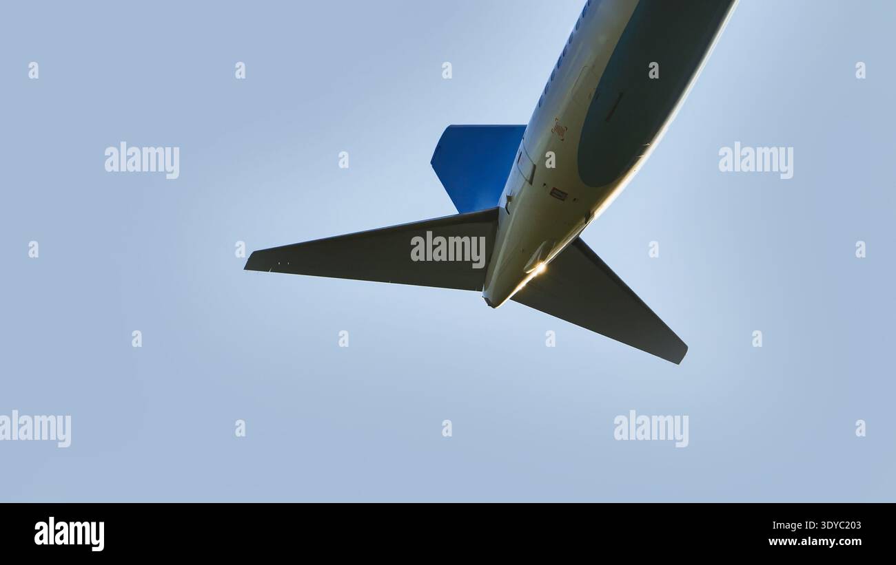 Visuale ad angolo basso della coda di un aereo commerciale che vola contro un cielo azzurro Foto Stock
