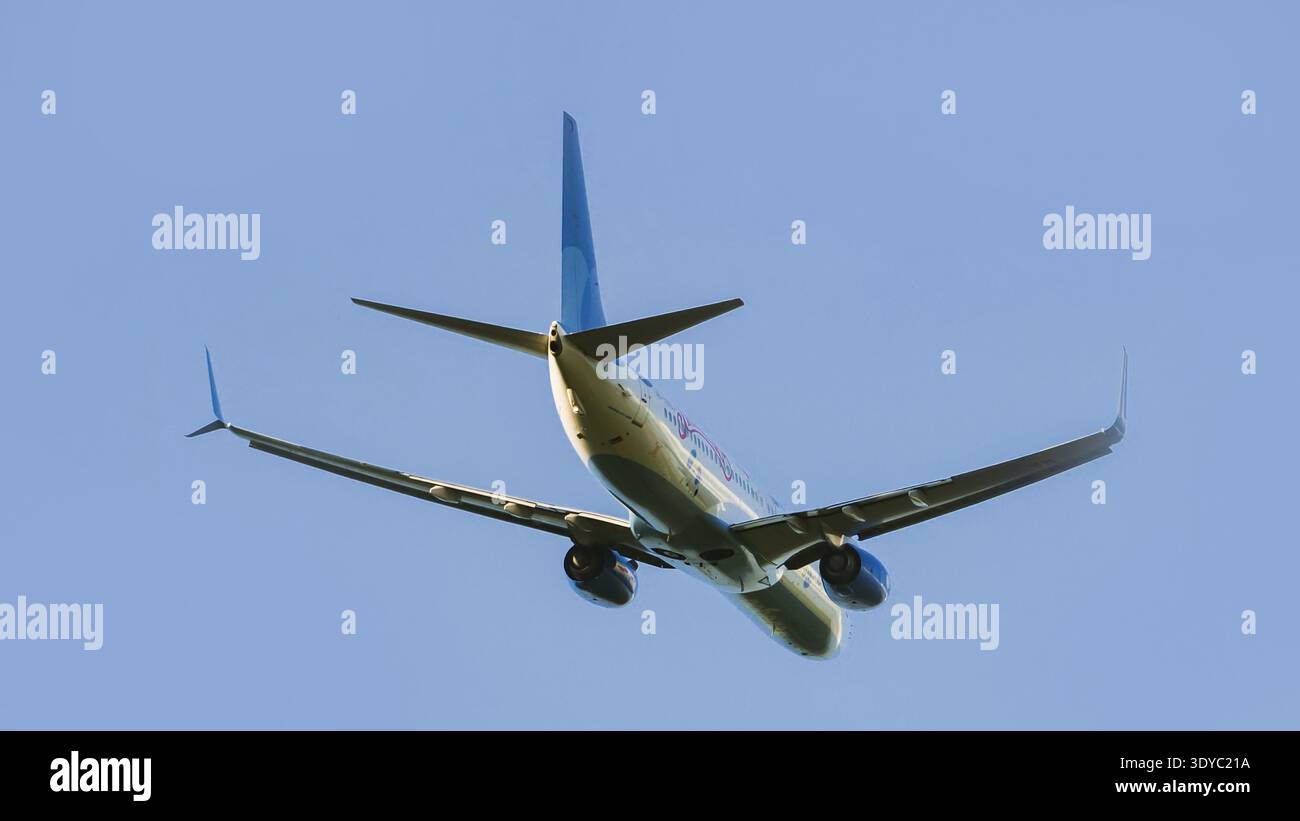 Aereo passeggeri commerciale in decollo, che sale in un cielo blu limpido. Vista ad angolo basso dal basso. Foto Stock