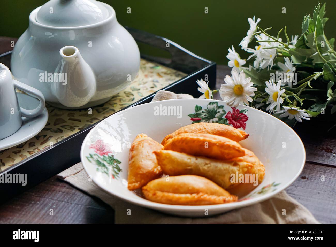 Sei spugne di curry dorate disposte su un piatto floreale su sfondo di legno scuro. Foto Stock