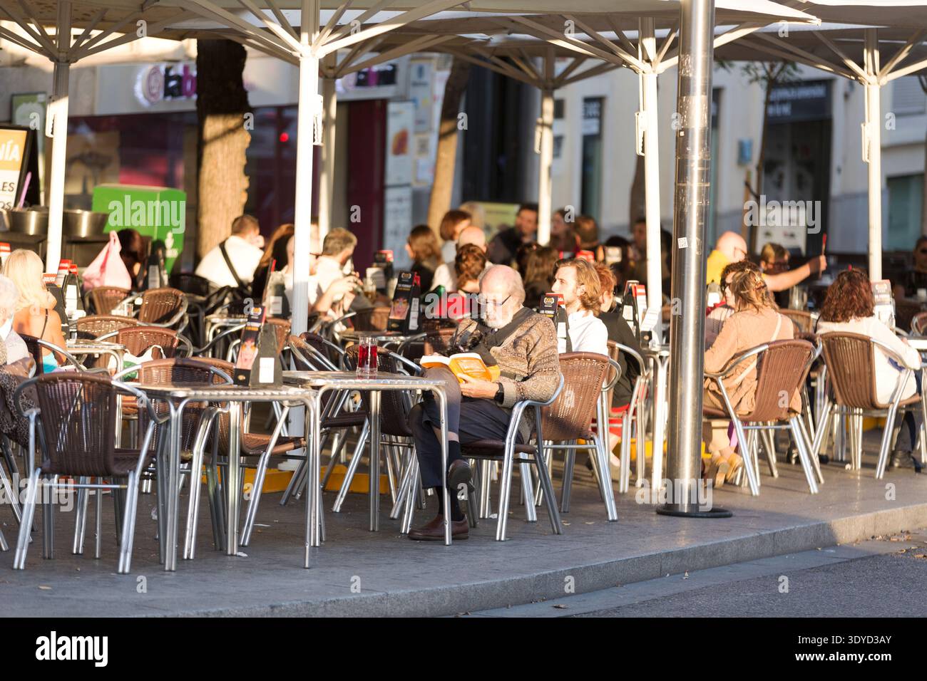 Persone che si rilassano in una terrazza soleggiata all'aperto durante l'ora d'oro a Madrid, Spagna. Foto Stock