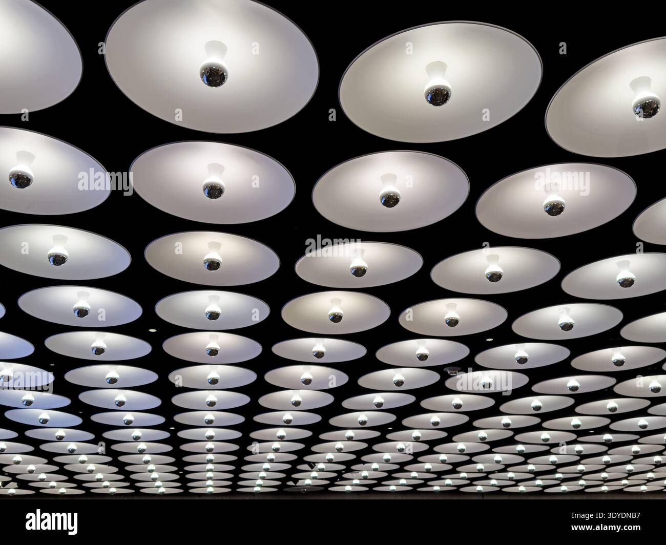 Una serie di lampade da soffitto si estende fino alla distanza nella lobby dell'edificio di New York City. Foto Stock