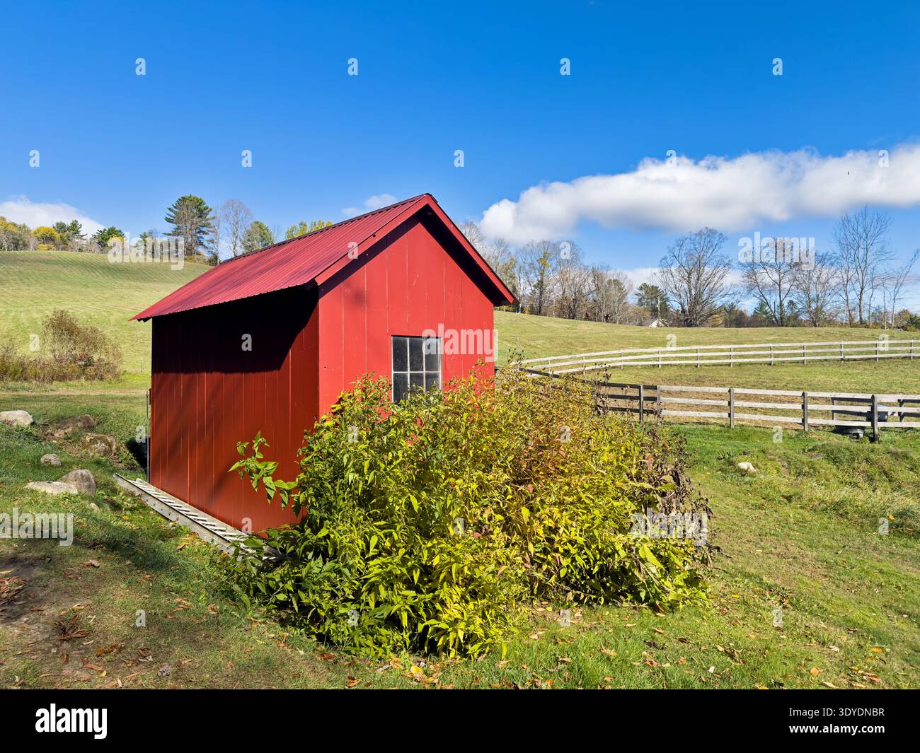 Una recinzione di legno delinea un corral vicino a un piccolo capannone rosso in una fattoria vicino a East Topsham, Vermont. Foto Stock