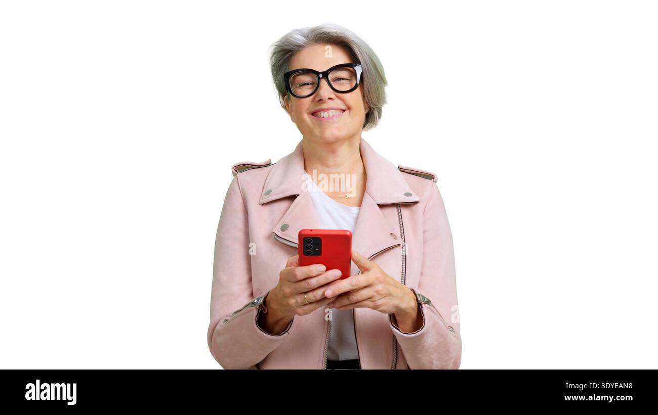 Donna anziana sorridente alla fotocamera, con uno smartphone rosso Foto Stock