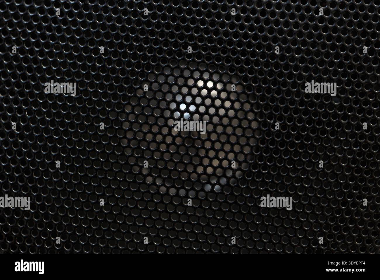 Primo piano di una griglia dell'altoparlante scura con un luminoso spot centrale. Design tecnologico astratto e futuristico. Foto Stock