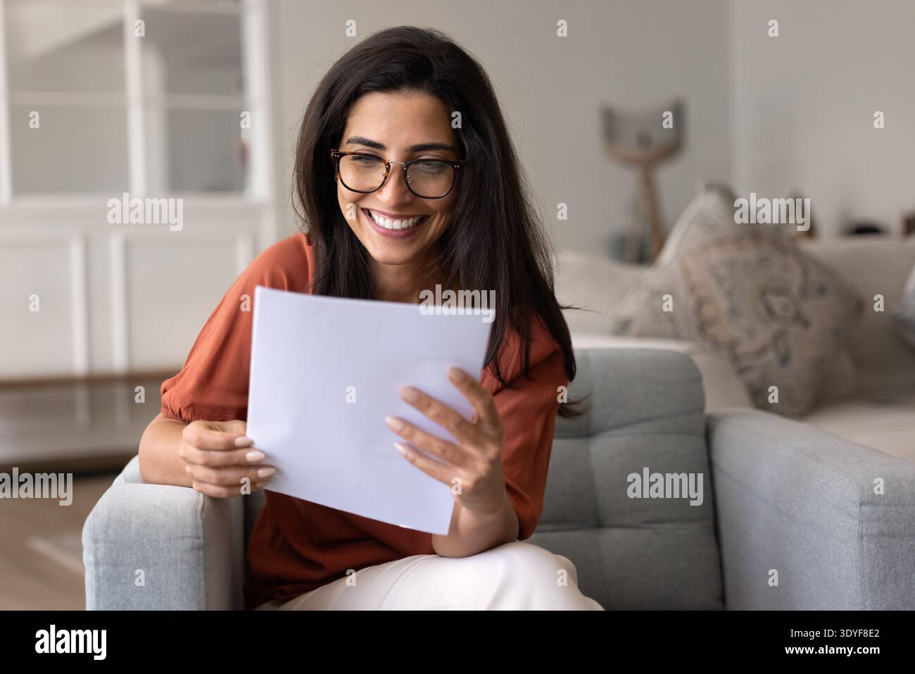 Bella donna brasiliana sorridente mentre legge una lettera con buone notizie Foto Stock