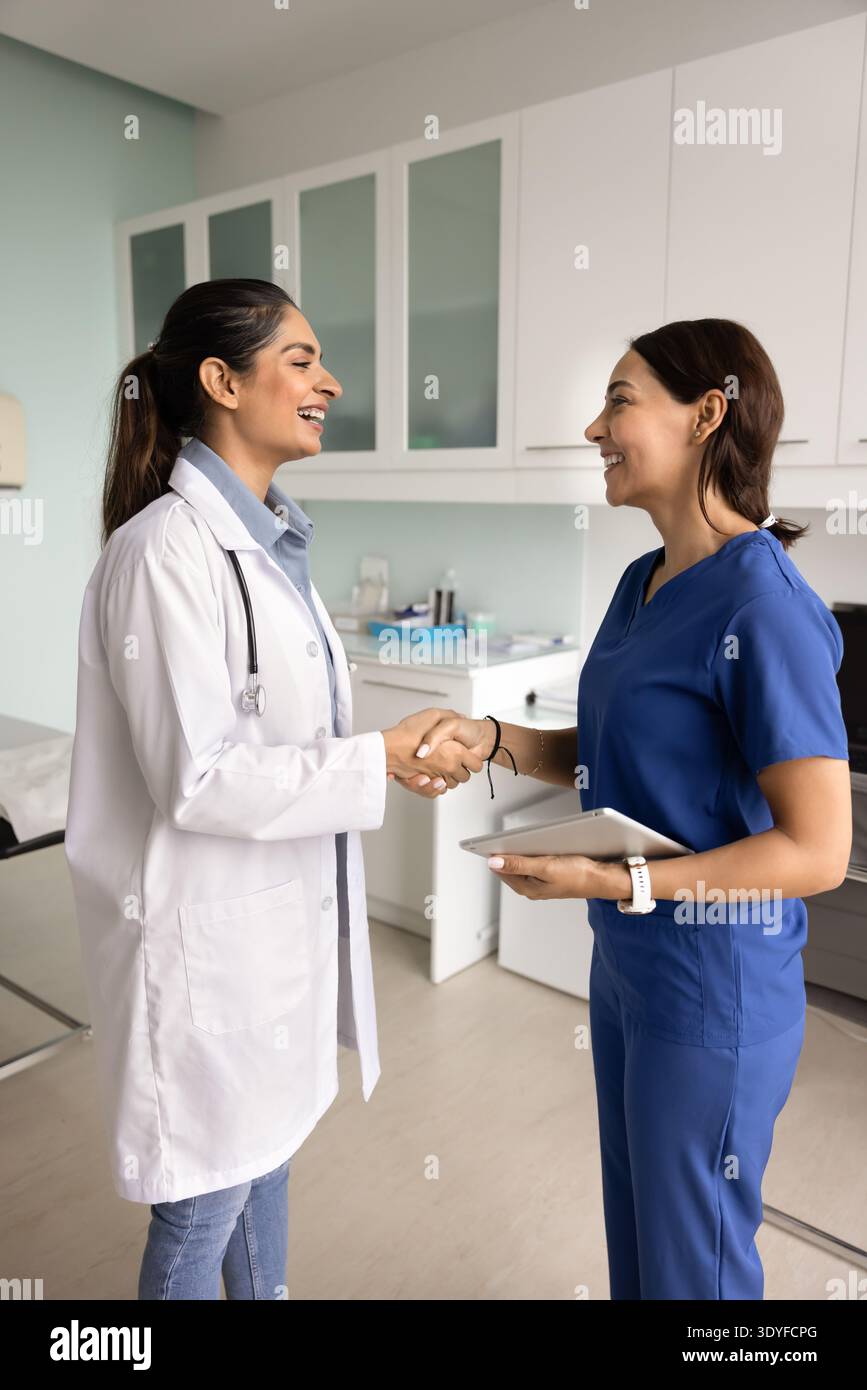 Medici sorridenti che stringono la mano in una clinica moderna Foto Stock